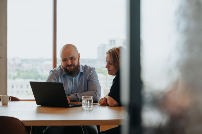 Jorne van Helvert kijkt samen met een klant op en laptop